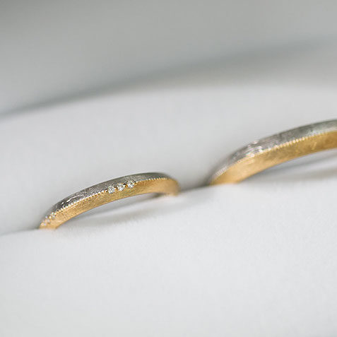 プラチナ950とK18イエローゴールドの結婚指輪 コンビネーションの結婚指輪。プラチナ950とK18イエローゴールドを使用し、表面にはダイヤモンド加工を施しました。レディースアップ写真。