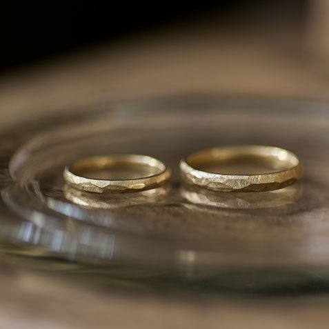 K18イエローゴールドの結婚指輪 ガラスのお皿に並べたK18イエローゴールドの結婚指輪のペアショット。