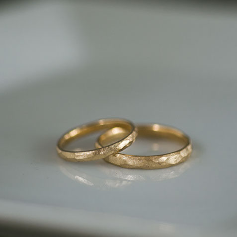 K18イエローゴールドの結婚指輪 陶器の器に並べたK18イエローゴールドの結婚指輪のペアショット。